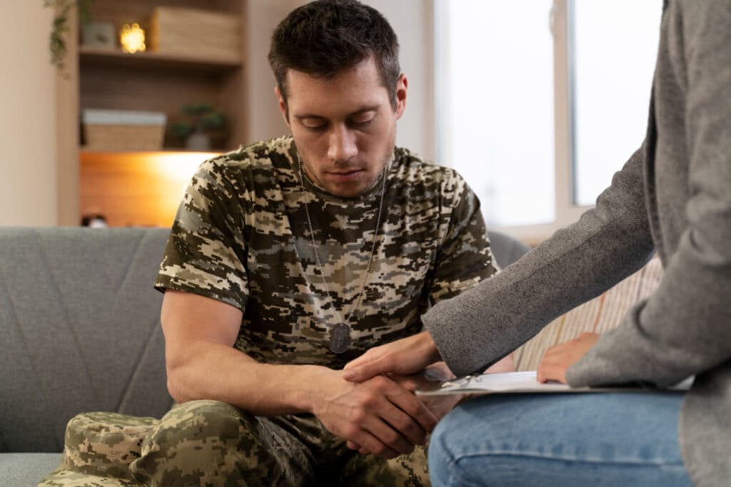 A male patient opening up about his PTSD with his therapist; call us if you're suffering from mental health issues.